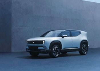 Front three-quarter view of the new Honda 0 α (Alpha) electric SUV concept in light silver, showcasing its futuristic illuminated 'H' logo light bar, unveiled at the Japan Mobility Show 2025.