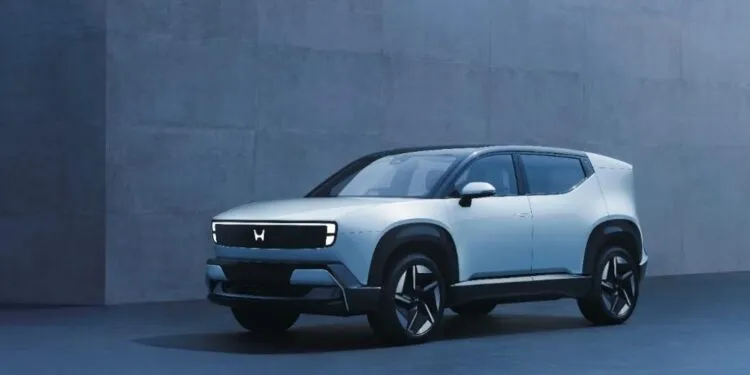 Front three-quarter view of the new Honda 0 α (Alpha) electric SUV concept in light silver, showcasing its futuristic illuminated 'H' logo light bar, unveiled at the Japan Mobility Show 2025.