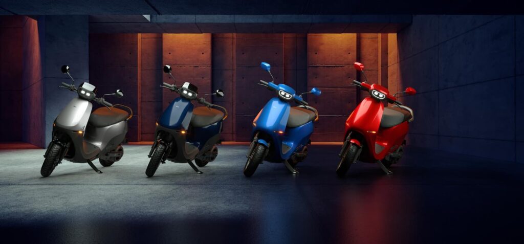 Ola Gets ARAI approval for 4680 Bharat Cell BatteryFour Ola S1 electric scooters in different colors (silver, dark blue, light blue, red) parked in an urban-style garage setting, showcasing the range of available colors.