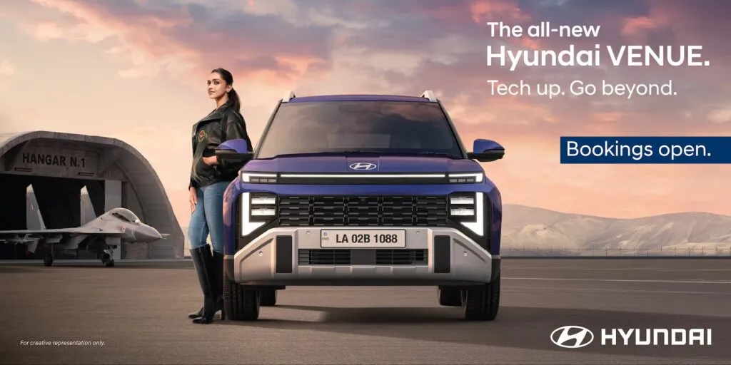 Front view of the all-new 2025 Hyundai Venue in Mystic Sapphire blue, parked near an aircraft hangar, with text 'Bookings Open'