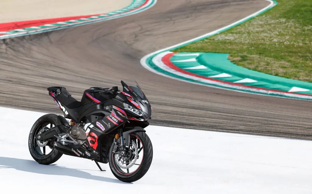 Aprilia RS 457 GP Replica sports bike on a racetrack, featuring upgraded equipment and graphics inspired by the Aprilia RS-GP MotoGP racing machine.
