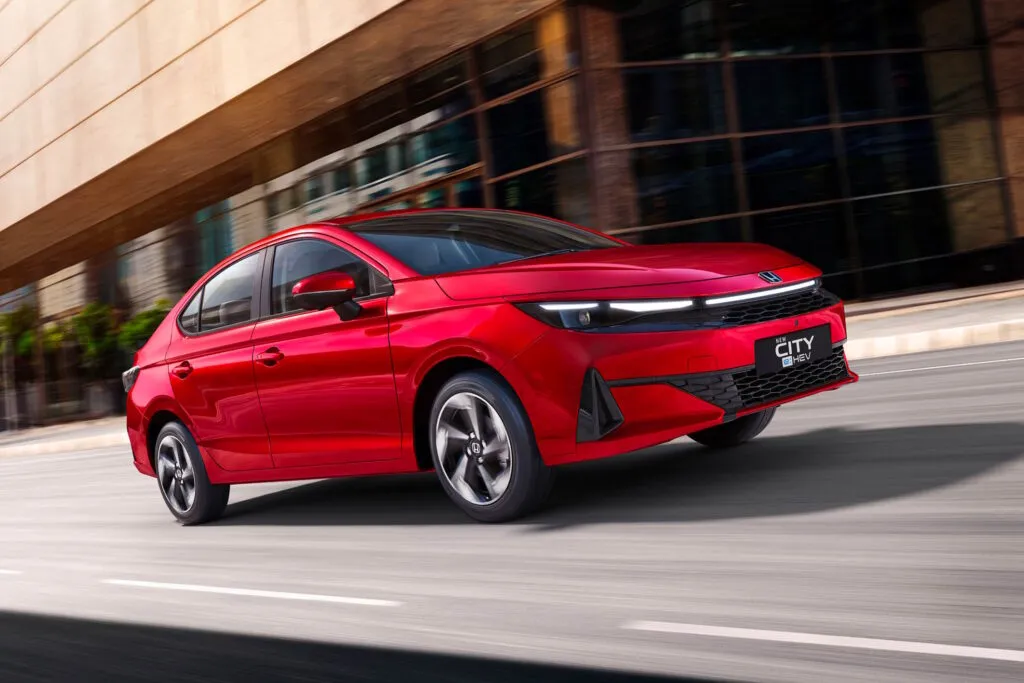 Red Honda City e:HEV sedan driving on a city street